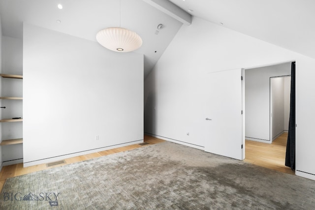 spare room featuring light hardwood / wood-style floors and vaulted ceiling with beams