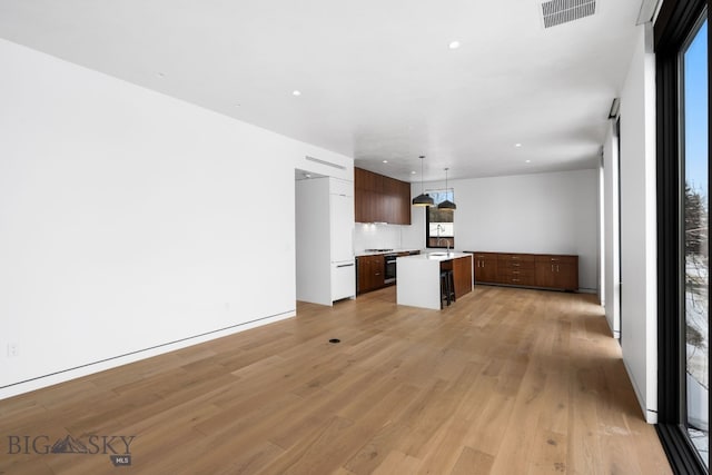 kitchen featuring sink, a center island, light hardwood / wood-style floors, tasteful backsplash, and hanging light fixtures