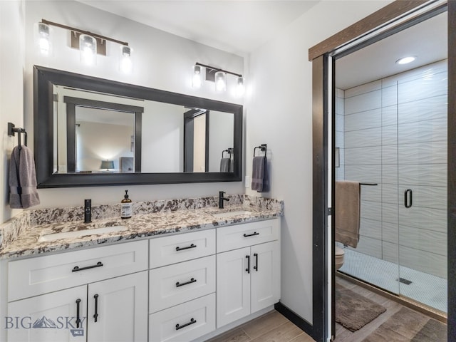 bathroom featuring vanity, toilet, a shower with shower door, and hardwood / wood-style floors