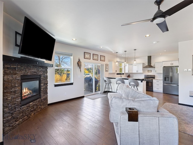 living room featuring dark wood-type flooring, a fireplace, and ceiling fan