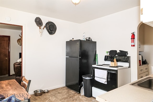 kitchen featuring white electric stove, black refrigerator, and sink