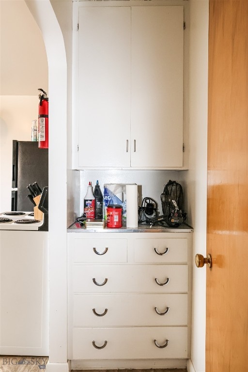 bar with white cabinets and black refrigerator