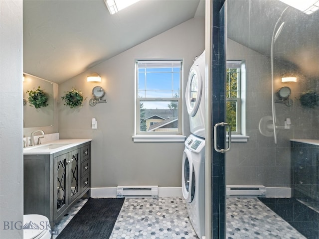 bathroom with a baseboard radiator, stacked washing maching and dryer, walk in shower, vaulted ceiling, and vanity