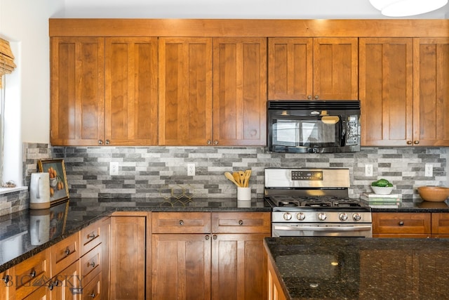 kitchen featuring stainless steel range with gas stovetop, backsplash, and dark stone counters