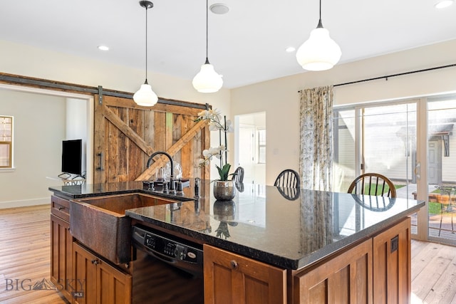 kitchen with sink, light wood-type flooring, dishwasher, a barn door, and pendant lighting