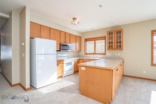 kitchen featuring white appliances, sink, kitchen peninsula, and light colored carpet