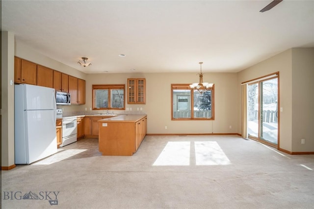 kitchen with white appliances, a notable chandelier, a kitchen island, light carpet, and decorative light fixtures