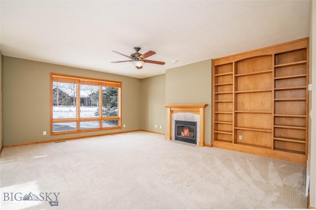 unfurnished living room with a tiled fireplace, ceiling fan, and carpet