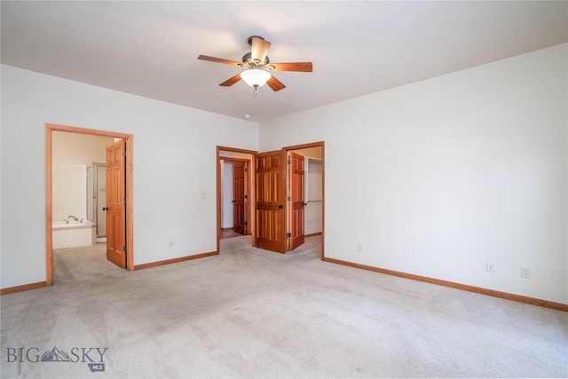 unfurnished bedroom with light carpet, connected bathroom, a spacious closet, and ceiling fan