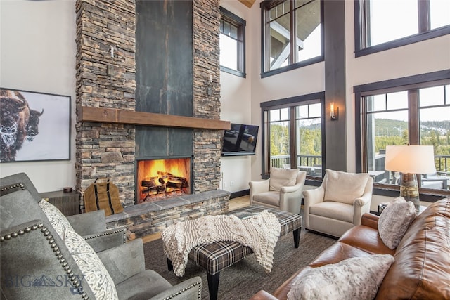 living room featuring a stone fireplace and a towering ceiling