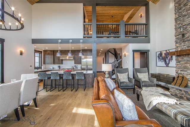 living room featuring wooden ceiling, high vaulted ceiling, light wood-type flooring, a notable chandelier, and beam ceiling