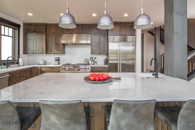 kitchen with a large island, sink, decorative light fixtures, and appliances with stainless steel finishes