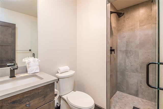 bathroom with vanity, toilet, and a shower with door