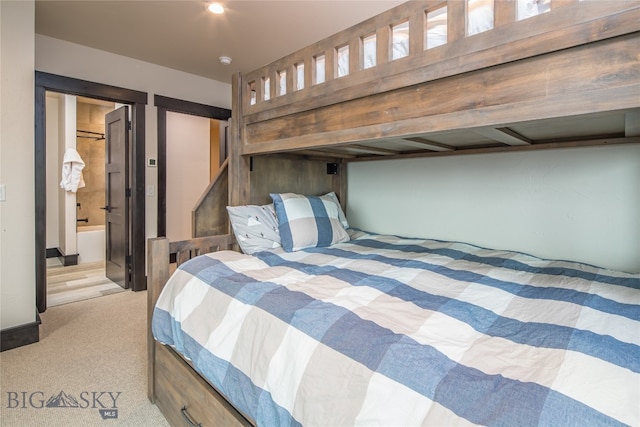 bedroom featuring connected bathroom and light carpet