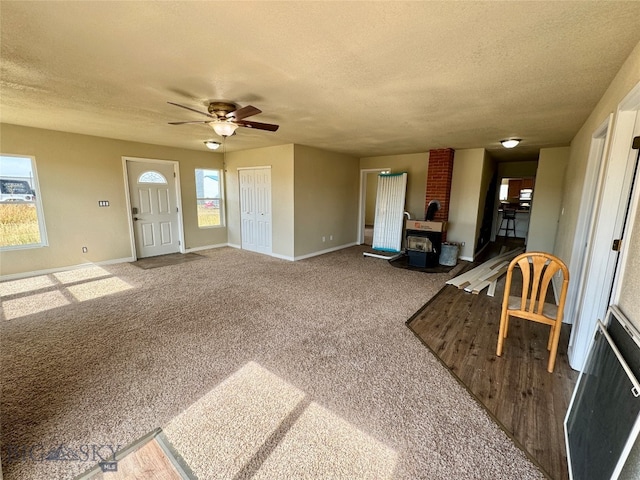 carpeted living room with a textured ceiling, a wood stove, and plenty of natural light