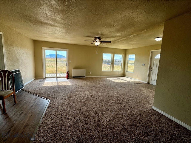 carpeted empty room featuring ceiling fan, plenty of natural light, and a textured ceiling