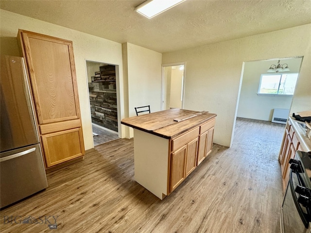 kitchen with light hardwood / wood-style flooring, a notable chandelier, and stainless steel fridge