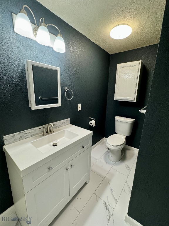 bathroom featuring vanity, a textured ceiling, and toilet