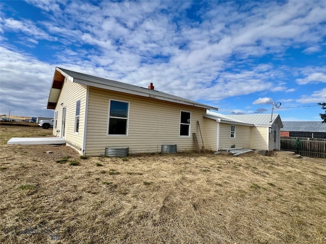 rear view of house featuring central AC unit and a yard