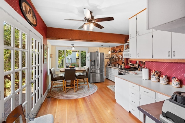 kitchen with stainless steel appliances, white cabinets, plenty of natural light, and light hardwood / wood-style flooring