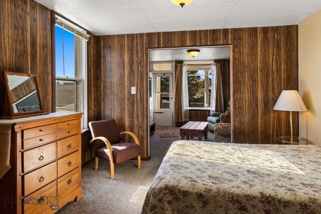 bedroom with dark colored carpet and wood walls