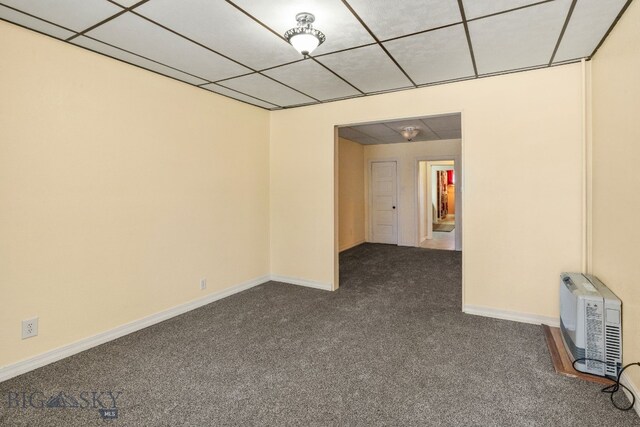 spare room featuring dark colored carpet and a drop ceiling