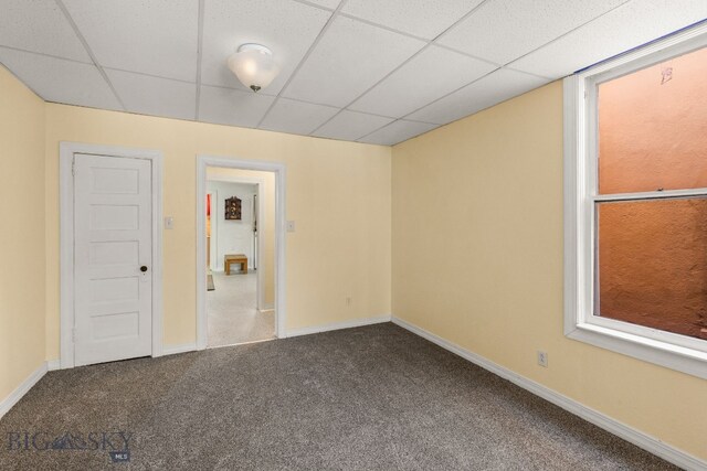 carpeted empty room featuring a drop ceiling