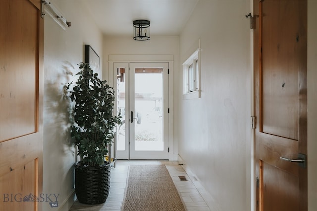 doorway to outside with a barn door, plenty of natural light, and light tile patterned floors