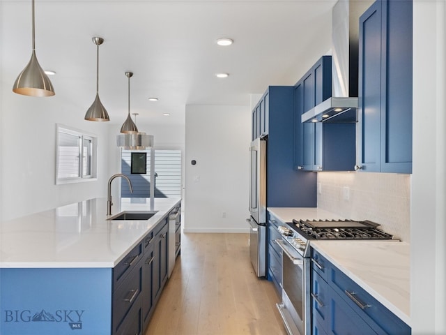 kitchen featuring stainless steel appliances, hanging light fixtures, sink, light hardwood / wood-style floors, and wall chimney exhaust hood