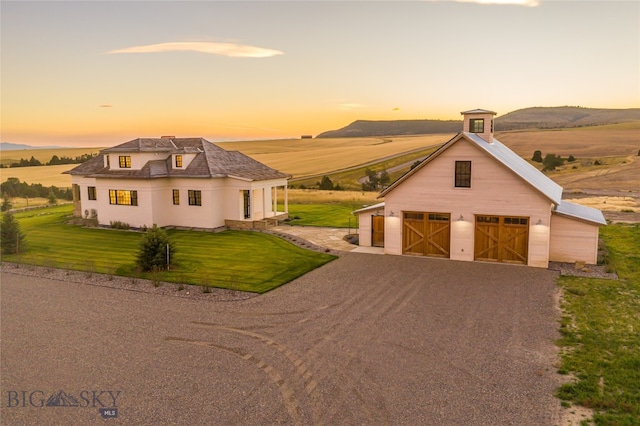 view of front facade with an outbuilding, a garage, a mountain view, and a yard