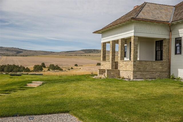 view of side of property with a rural view and a lawn