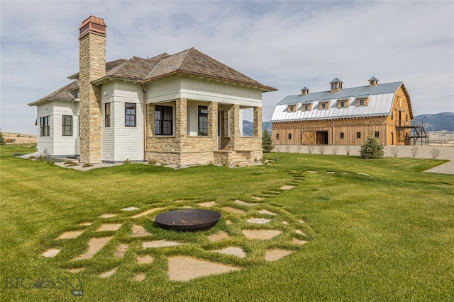 back of property with a lawn and a fire pit