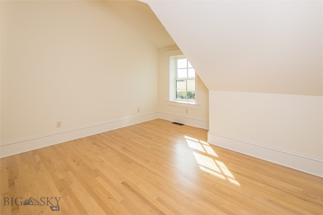 additional living space with light wood-type flooring and lofted ceiling