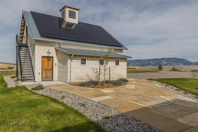 exterior space featuring a lawn, a mountain view, solar panels, and a patio