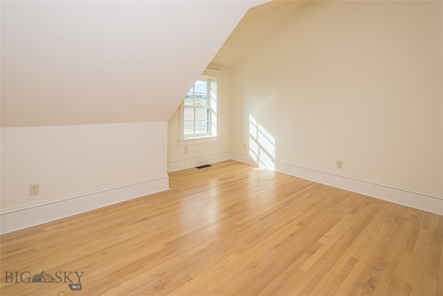 additional living space with light hardwood / wood-style floors and lofted ceiling