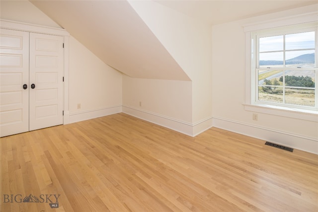 bonus room featuring light wood-type flooring and vaulted ceiling