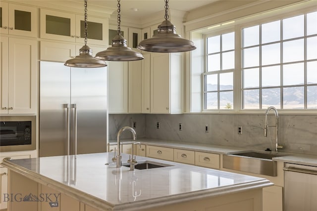 kitchen featuring stainless steel appliances, a center island with sink, sink, and pendant lighting