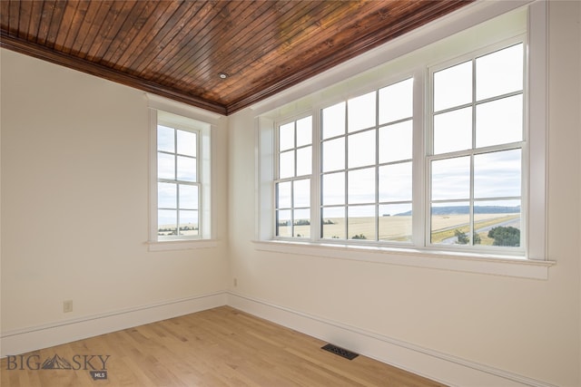 spare room featuring ornamental molding, plenty of natural light, light hardwood / wood-style floors, and wood ceiling