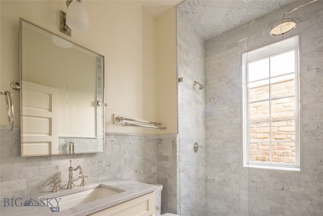 bathroom featuring tile walls, tiled shower, vanity, and toilet