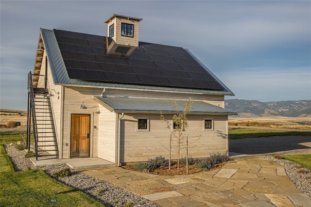 view of front of property featuring a mountain view and solar panels