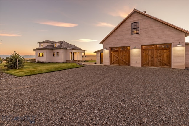 view of front of property featuring a garage, an outdoor structure, and a lawn