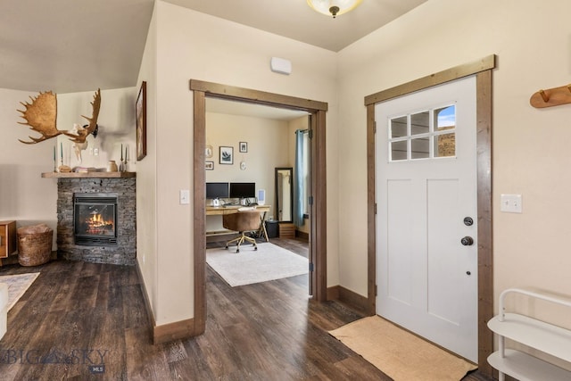 foyer entrance featuring dark hardwood / wood-style floors and a stone fireplace