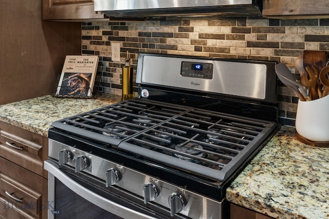 room details featuring dark brown cabinetry, tasteful backsplash, and stainless steel gas range