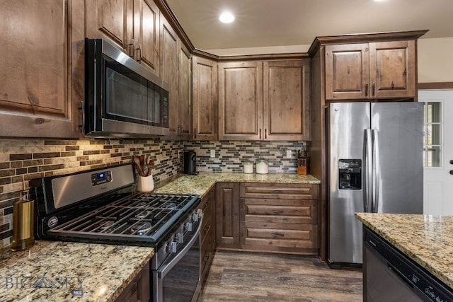 kitchen with tasteful backsplash, light stone counters, dark hardwood / wood-style flooring, and appliances with stainless steel finishes