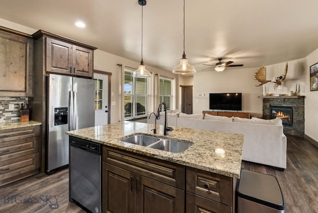 kitchen featuring dark brown cabinetry, sink, dark hardwood / wood-style flooring, a fireplace, and appliances with stainless steel finishes