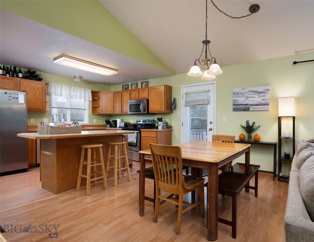 dining room with light hardwood / wood-style floors, lofted ceiling, and a notable chandelier