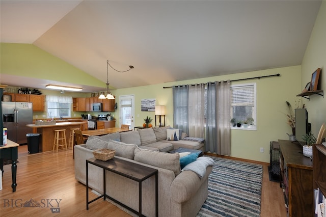 living room featuring light hardwood / wood-style floors, lofted ceiling, and a chandelier