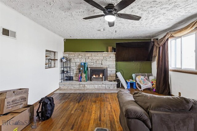 living room featuring a textured ceiling, ceiling fan, a fireplace, and hardwood / wood-style floors