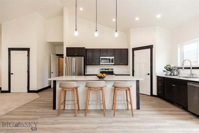 1511 Pistolero Way, Belgrade, MT 59714 - kitchen featuring stainless steel appliances, a sink, high vaulted ceiling, a kitchen bar, and light countertops