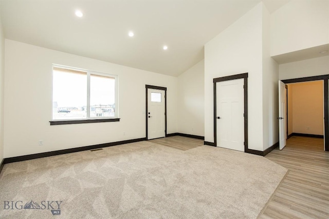 1511 Pistolero Way, Belgrade, MT 59714 - spare room with baseboards, recessed lighting, high vaulted ceiling, light wood finished floors, and light carpet